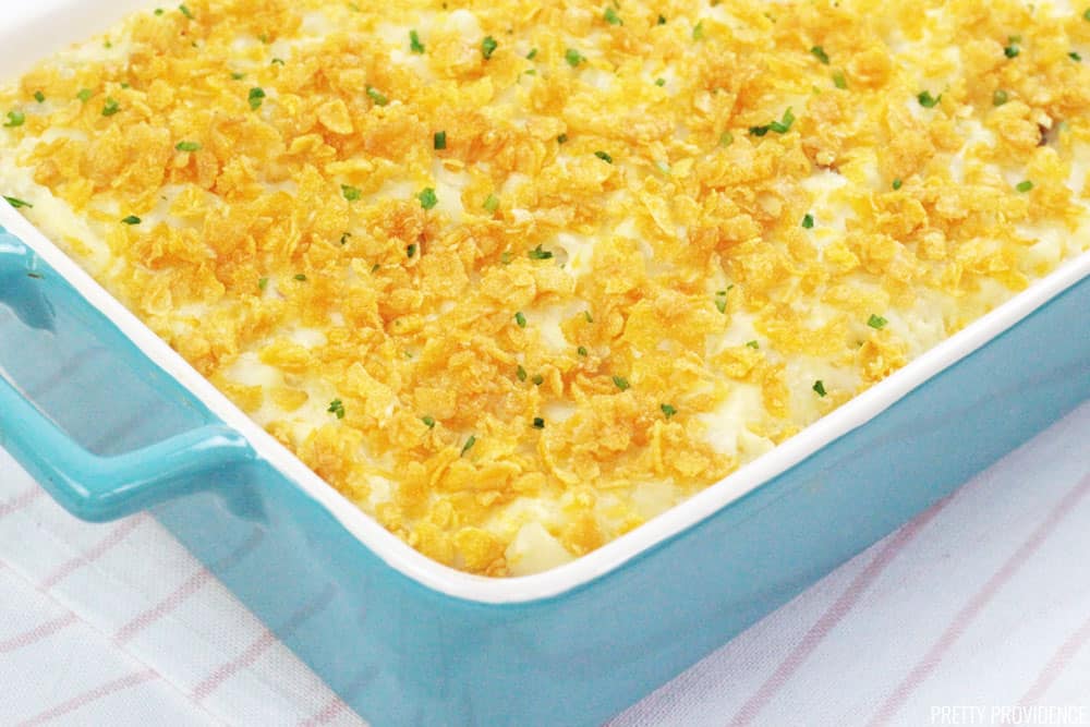 Potato Casserole AKA Funeral Potatoes in a blue 9x13 baking dish topped with cornflakes and chives.