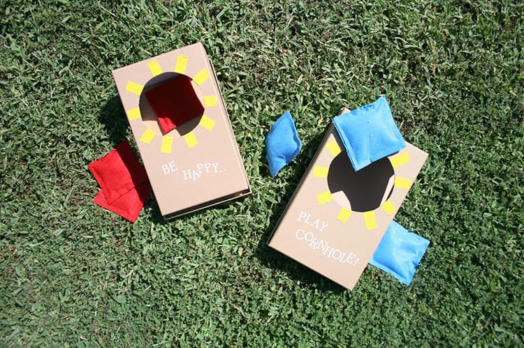 Mini cornhole boards with bean bags on green grass.