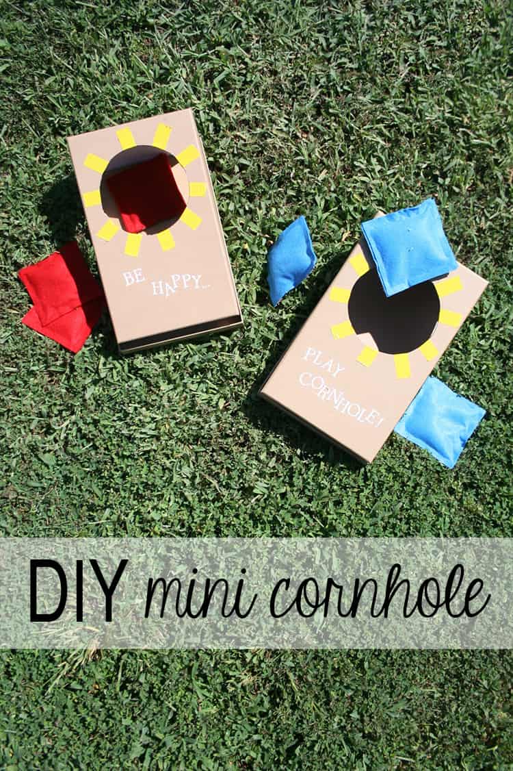 Mini cornhole boards with bean bags on green grass.