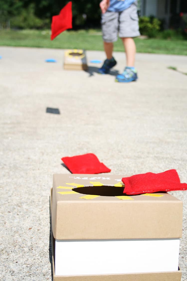 Red bean bags on a small cardboard corn hole set.