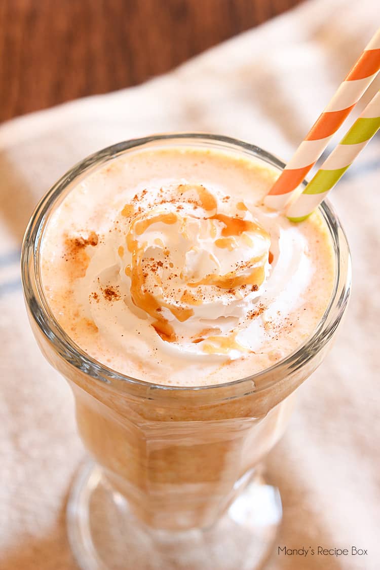 Close up shot of a pumpkin milkshake topped with whipped cream and caramel sauce