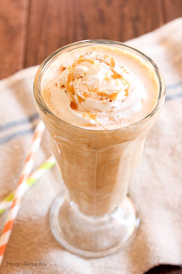 pumpkin caramel milkshake next to two straws on a cloth napkin