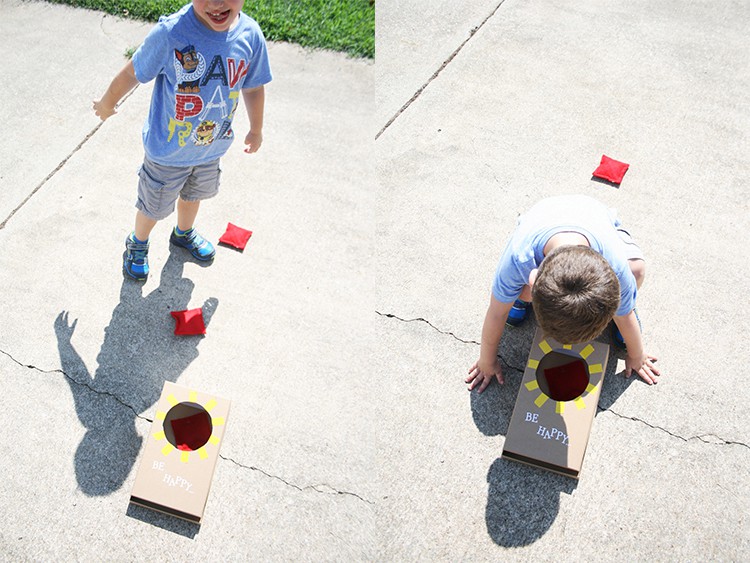 A small boy playing mini corn hole. 