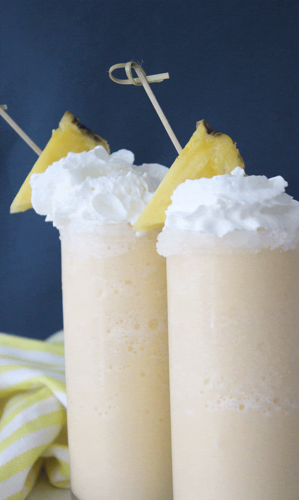 up close of two pina colada slushes in clear glasses against a navy background