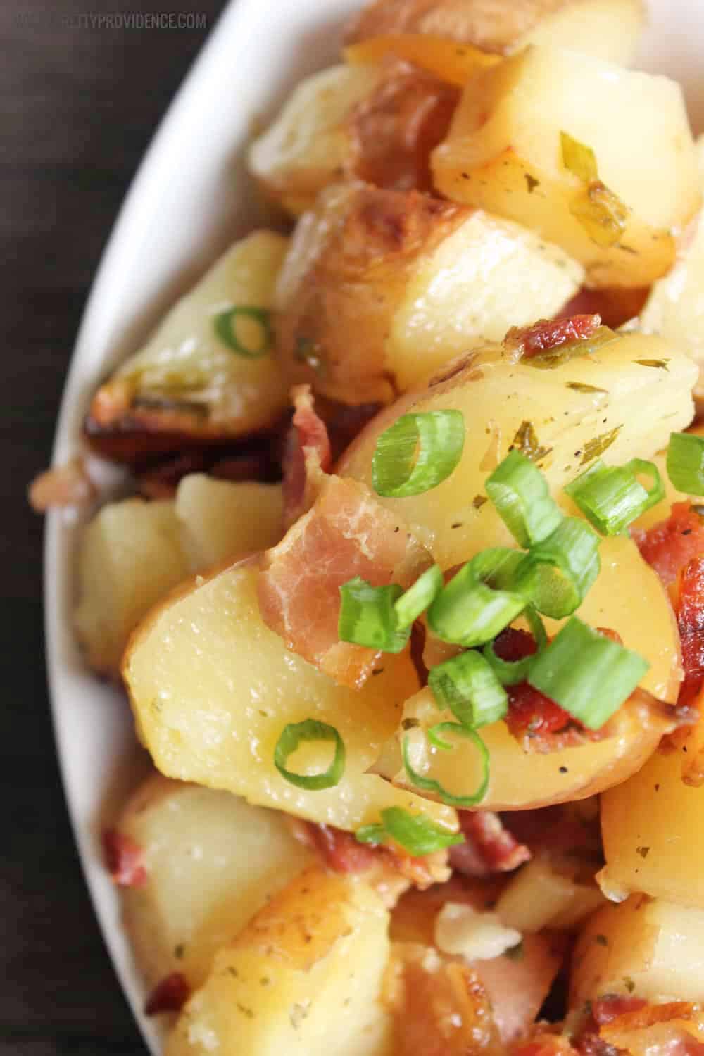 Slow Cooker ranch potatoes with garlic and bacon and green onions on top.