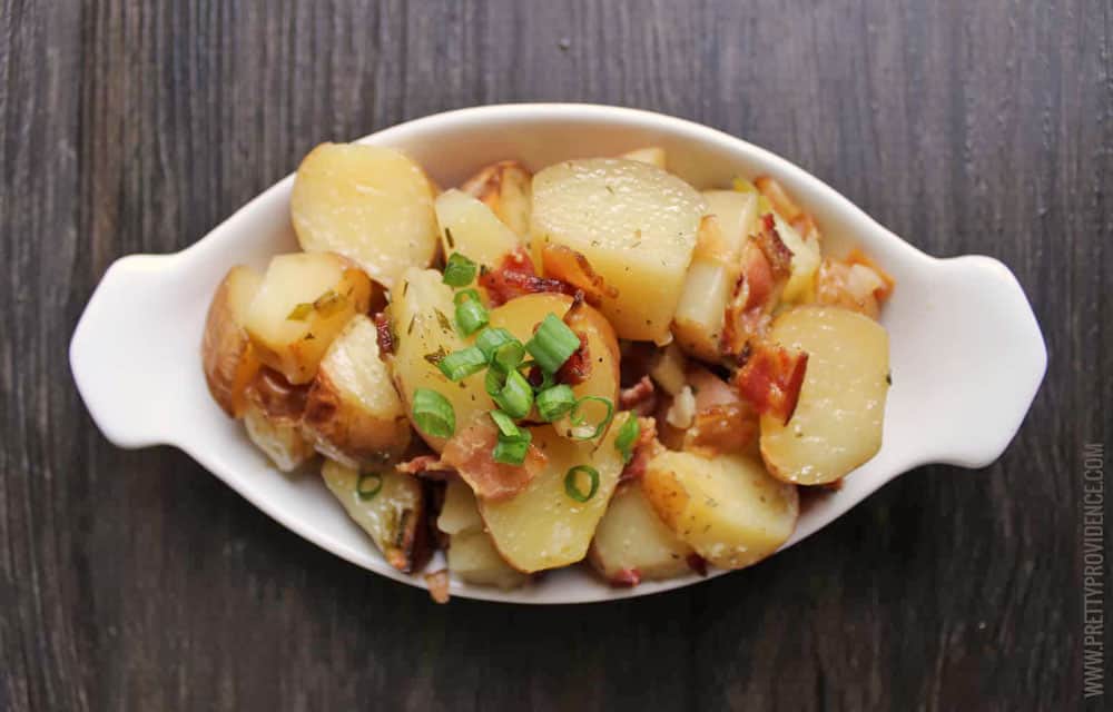 Slow Cooker Ranch Potatoes in a white serving dish topped with green onions and bacon