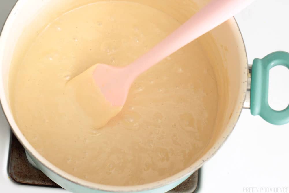 Melted marshmallow, butter and brown sugar in a large pot on the stove, pink silicone spatula.