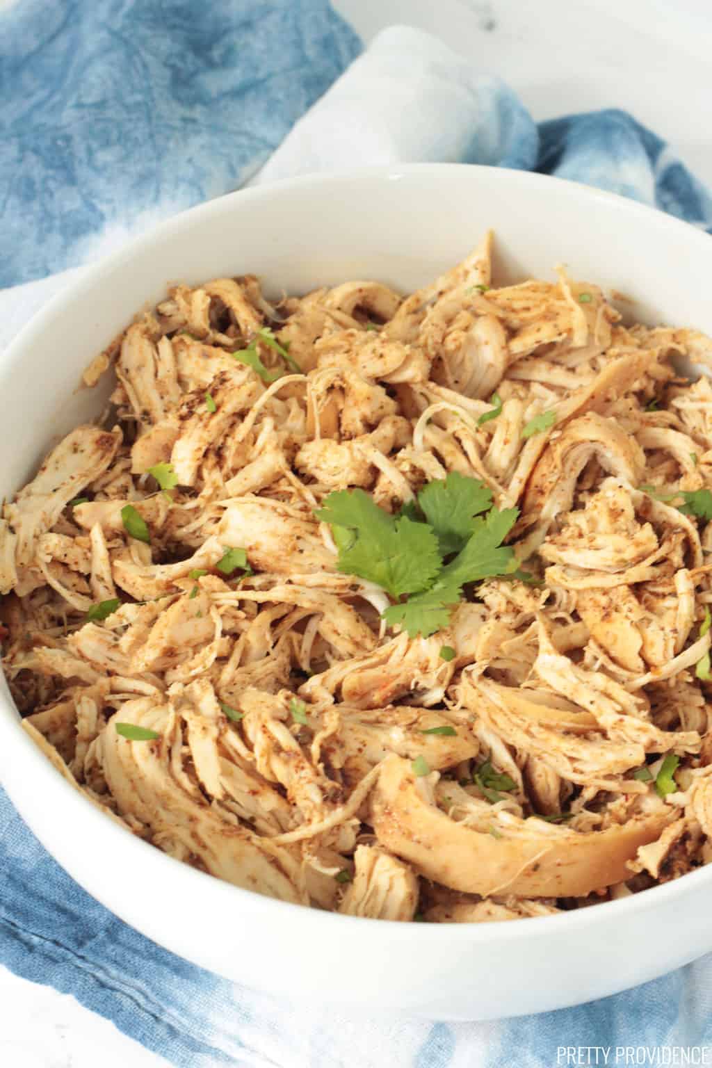 Shredded Mexican chicken in a white bowl with cilantro on top 
