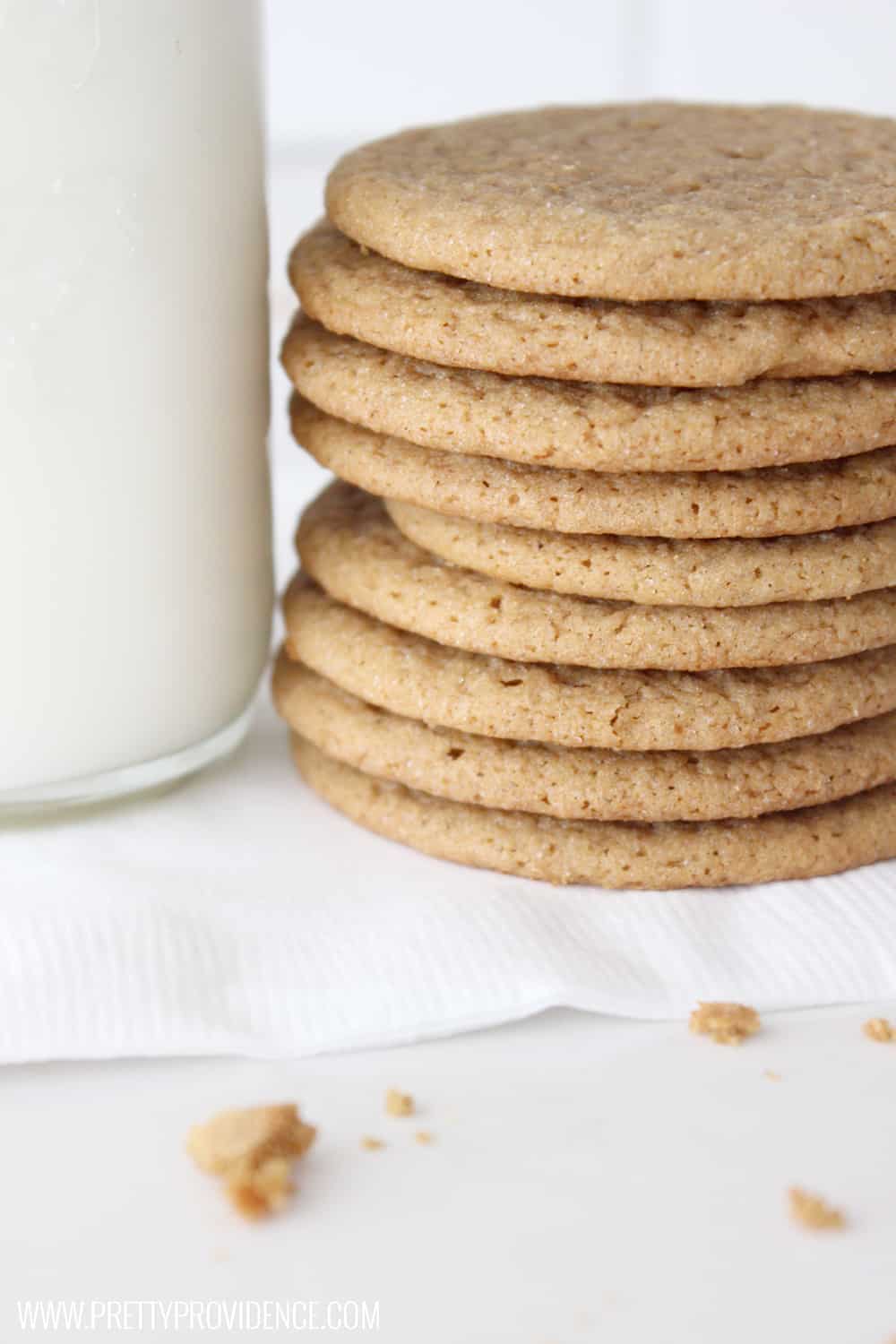 a stack of ginger snap cookies on a white napkin next to a glass of milk
