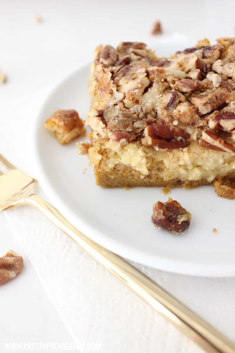 Close up shot of pumpkin dump cake on a white plate with crunchy walnut topping.