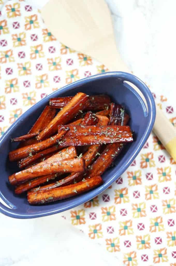 Roasted carrots with balsamic vinegar, brown sugar and herbs in a blue dish.
