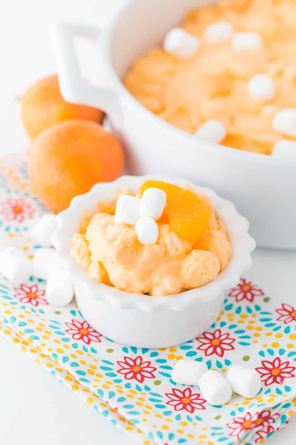 creamsicle orange fluff in white serving dishes with marshmallows on top