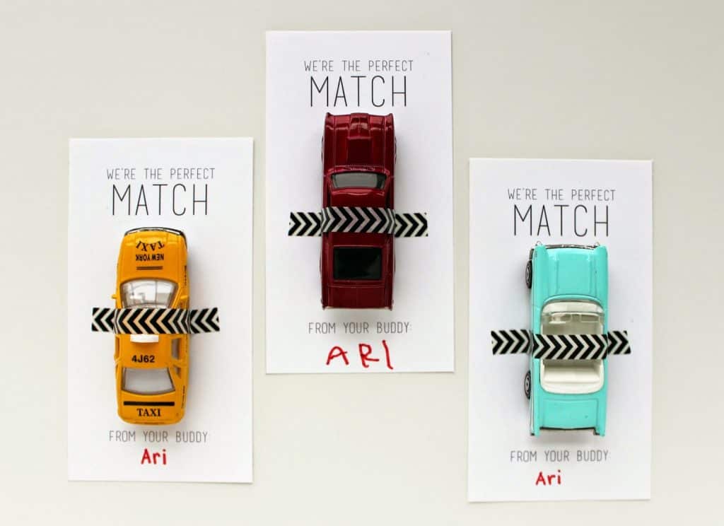 three matchbox car valentines for kids, one yellow car, red car and teal car with washi tape to hold them onto the cards.