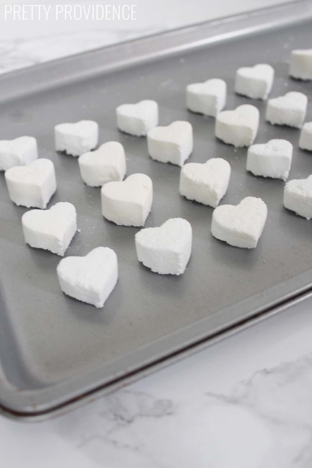 heart shaped toilet cleaning bombs on a grey cookie sheet on a marble counter