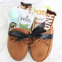 Men's moccasin slippers filled with treats and small gifts tied with a black ribbon