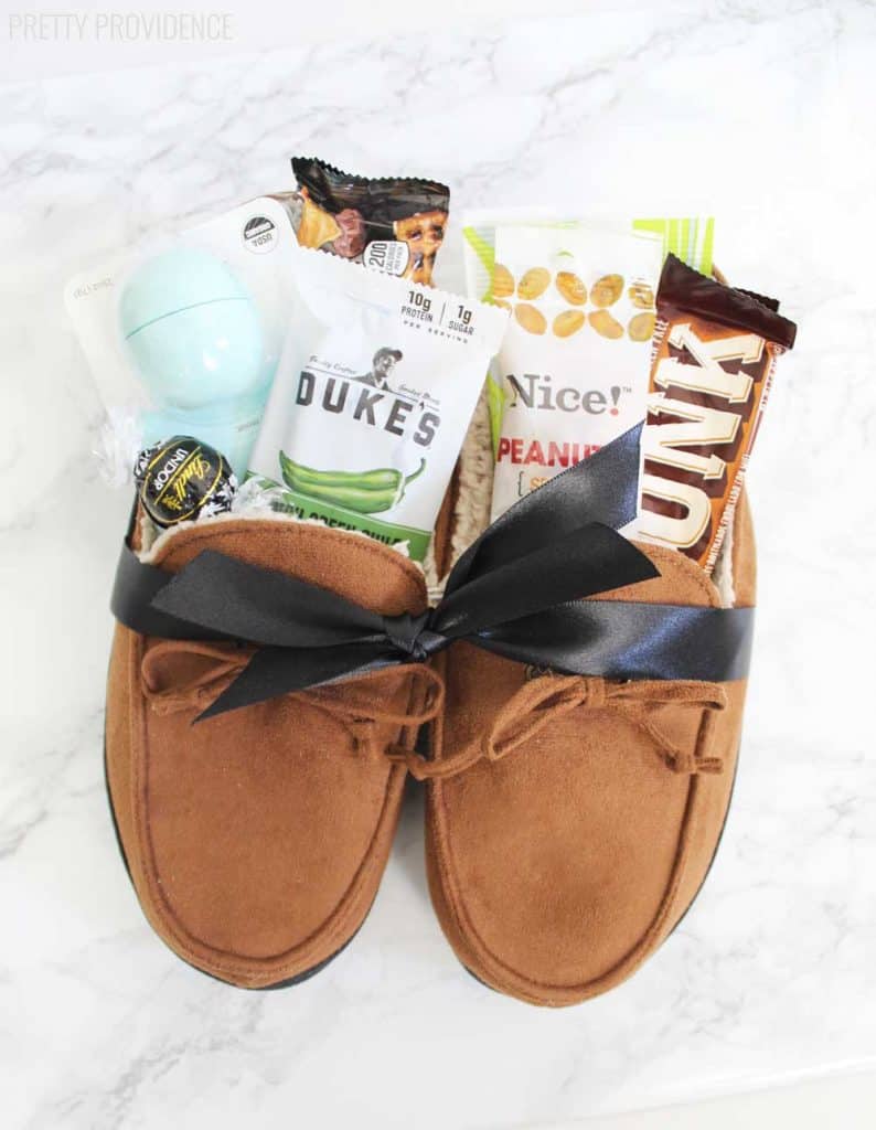 Men's moccasin slippers filled with treats and small gifts tied with a black ribbon