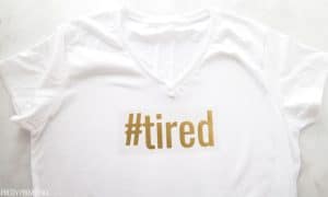 Cricut Iron-On design (gold iron-on vinyl "#tired") placed on a white t-shirt before ironing on