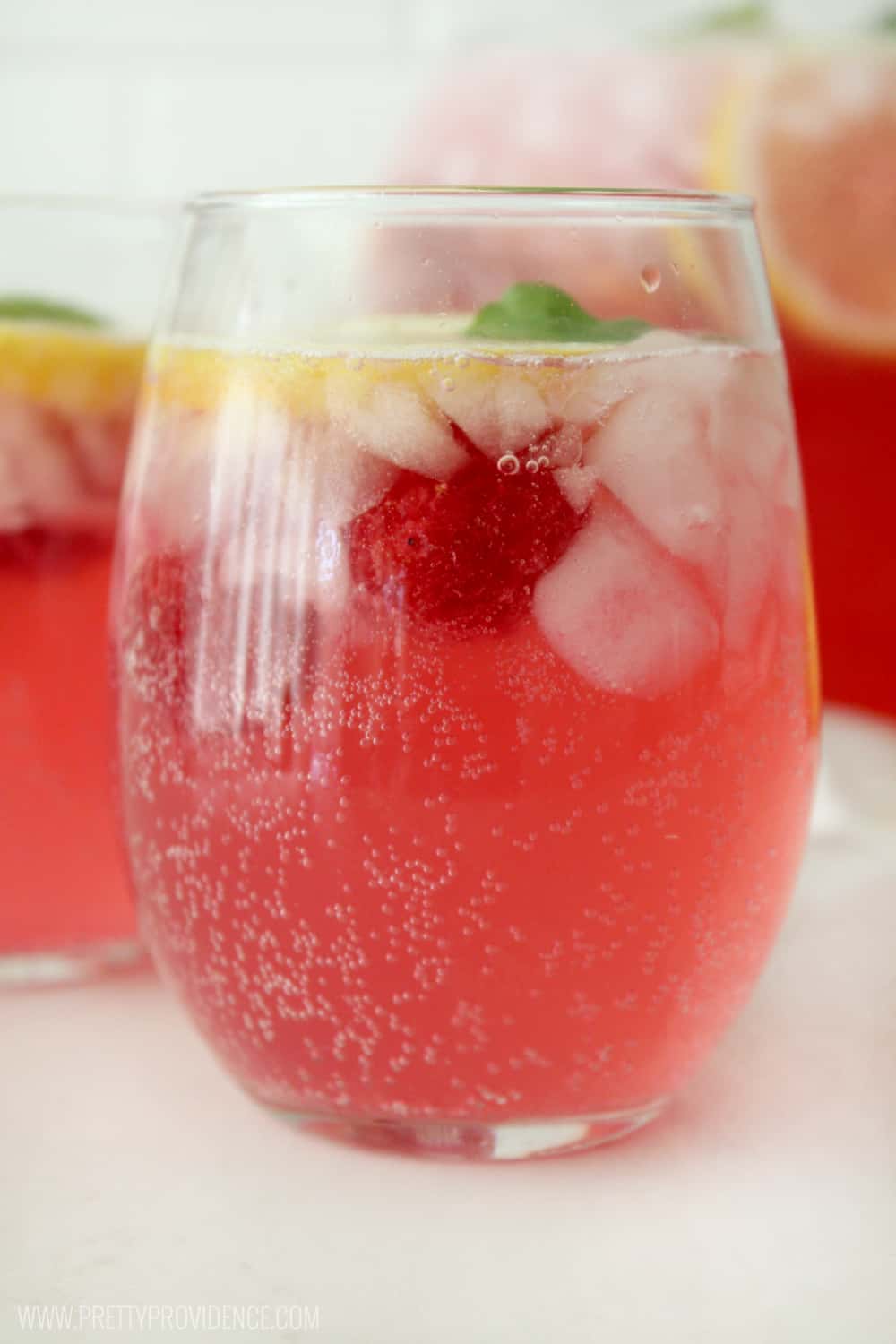 Raspberry, ice and lemon floating in a glass of homemade raspberry lemonade