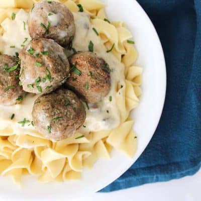 Bird's eye view of a white bowl of egg noodles with meatball stroganoff on top.