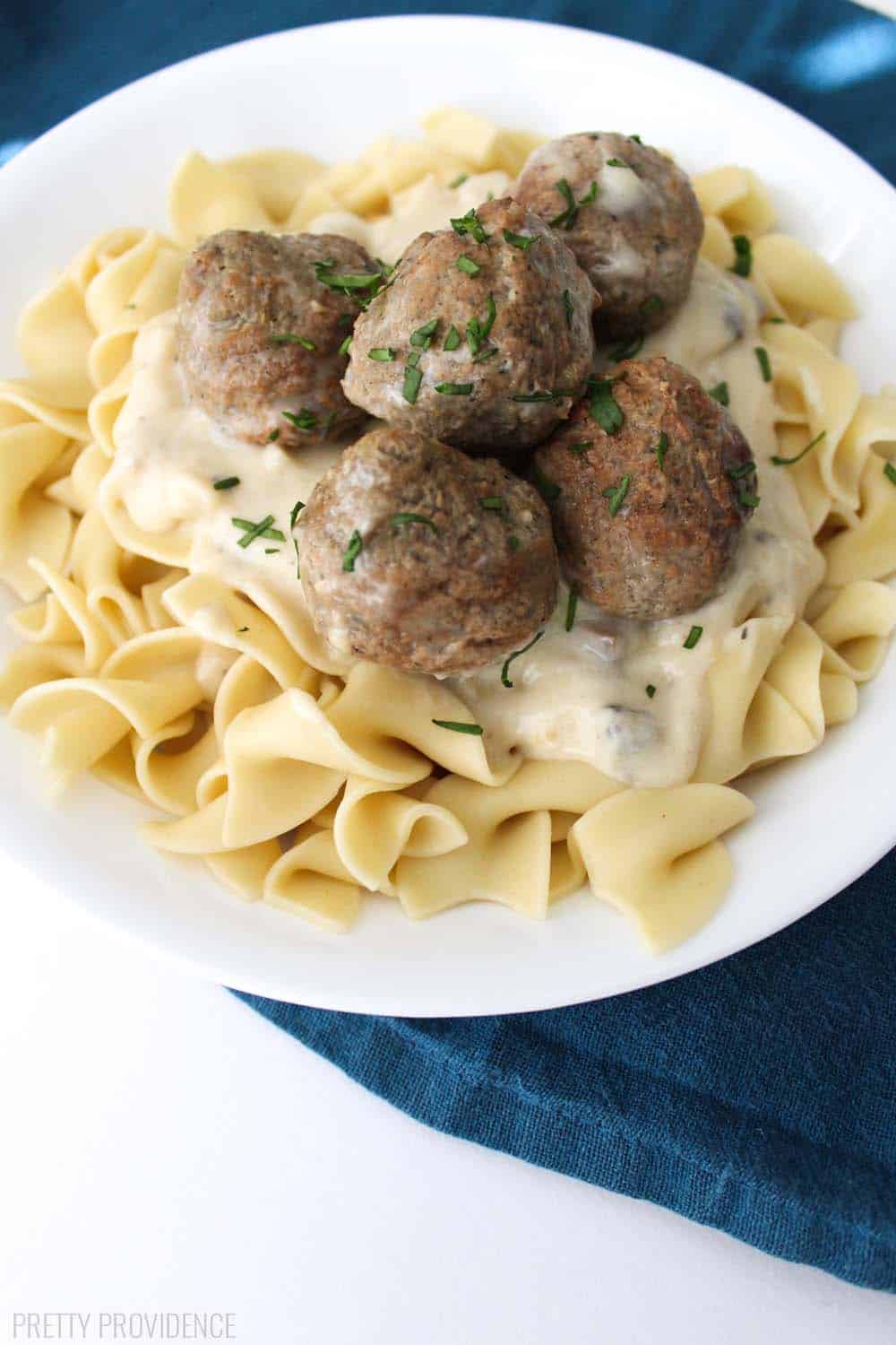 A bowl of noodles with meatballs and sauce on top. 
