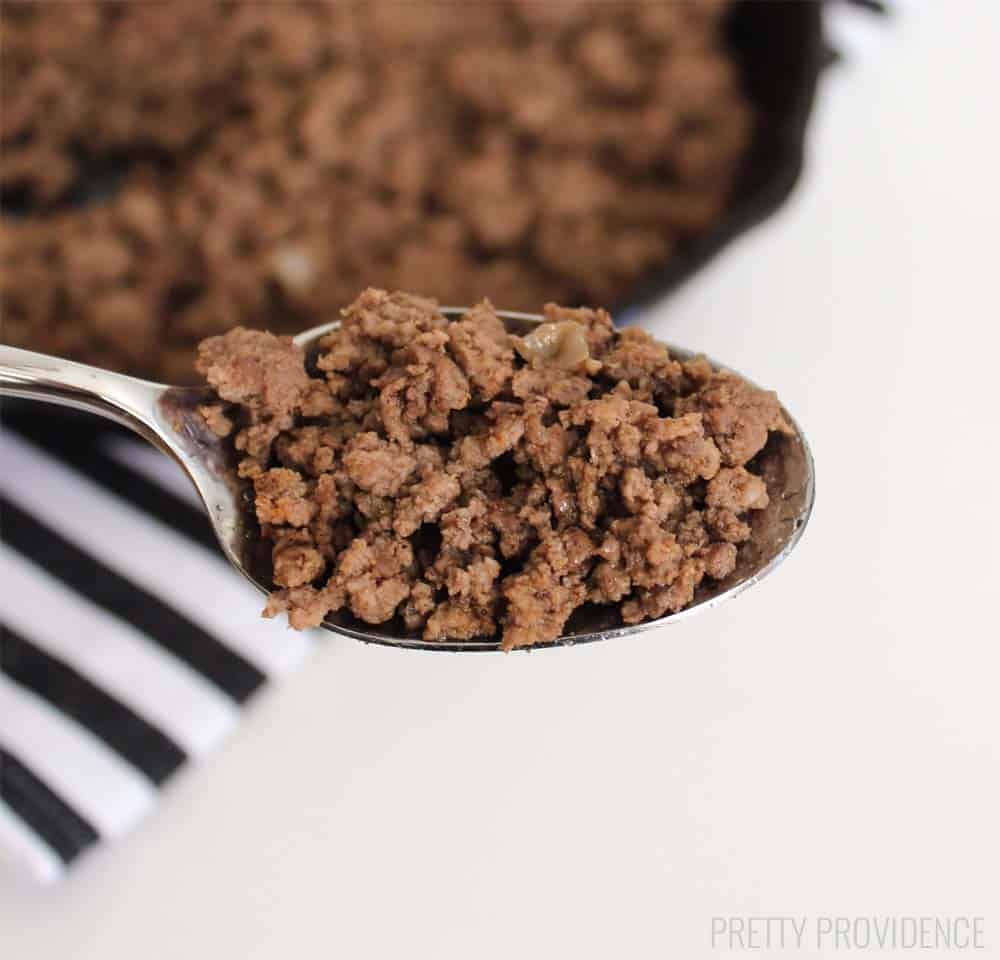 a spoon full of season ground beef above a pan of ground beef in the background