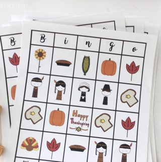 Thanksgiving Bingo free to print sheets stacked with gold-wrapped Rolo candy on the side.