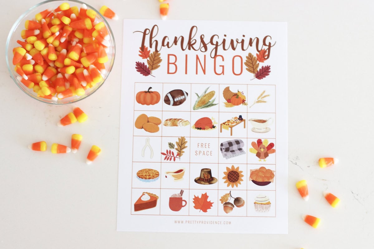 A Thanksgiving bingo card next to a bowl of candy corn used for markers. 