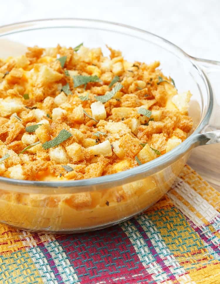 Savory Sweet Potato Casserole in a glass dish with sage breadcrumbs and fresh sage leaves on top.