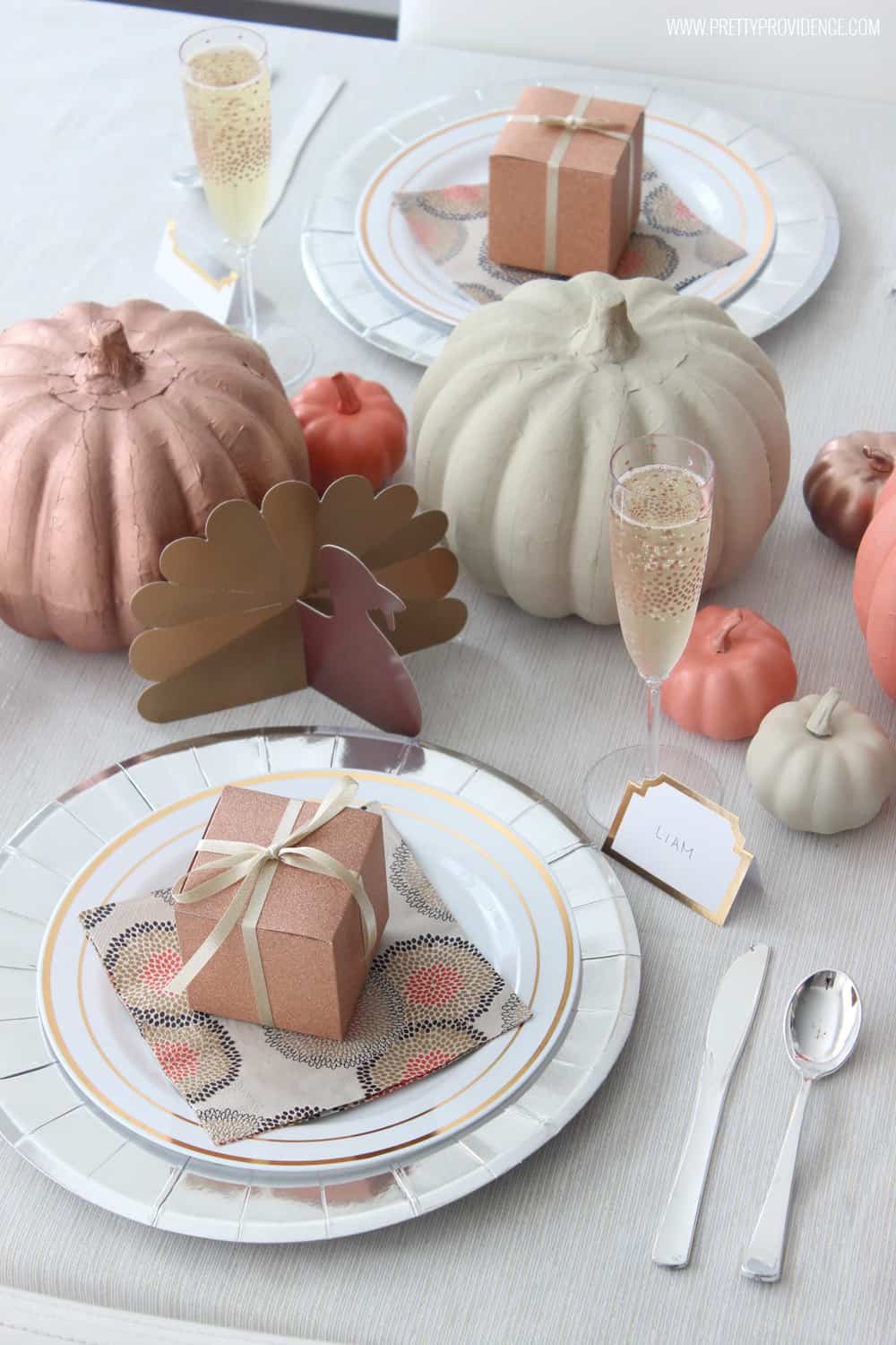 Thanksgiving table set with paper products - silver, white and copper craft pumpkins and paper turkeys.