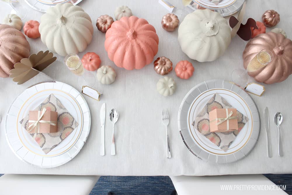 Thanksgiving Table set with paper products, overhead view. Orange, gold and cream pumpkins, silver chargers, and more.