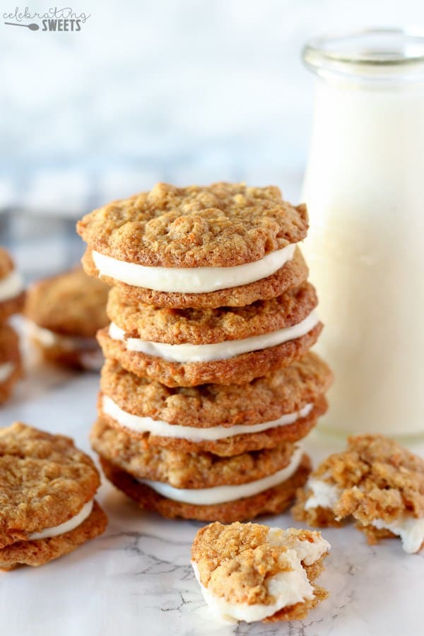 Carrot cake sandwich cookies stacked up next to a cup of milk