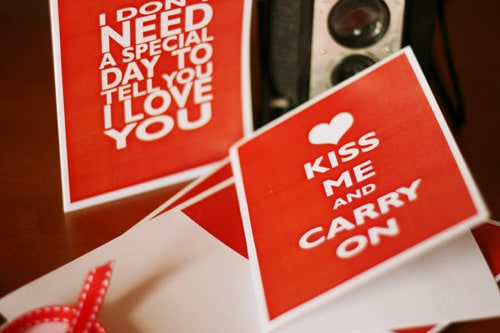 Valentine Card red with white letters that reads Kiss Me & Carry On inspired by the Keep Calm & Carry On posters well-known in pop culture.