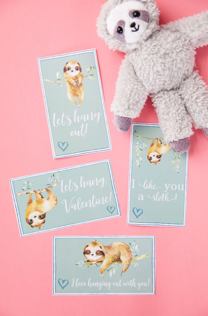 Sloth Valentines cards printed and set on pink background.