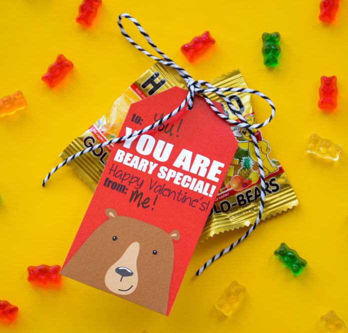 Bear Valentines with gummy bears attached with bakers twine on a yellow background.