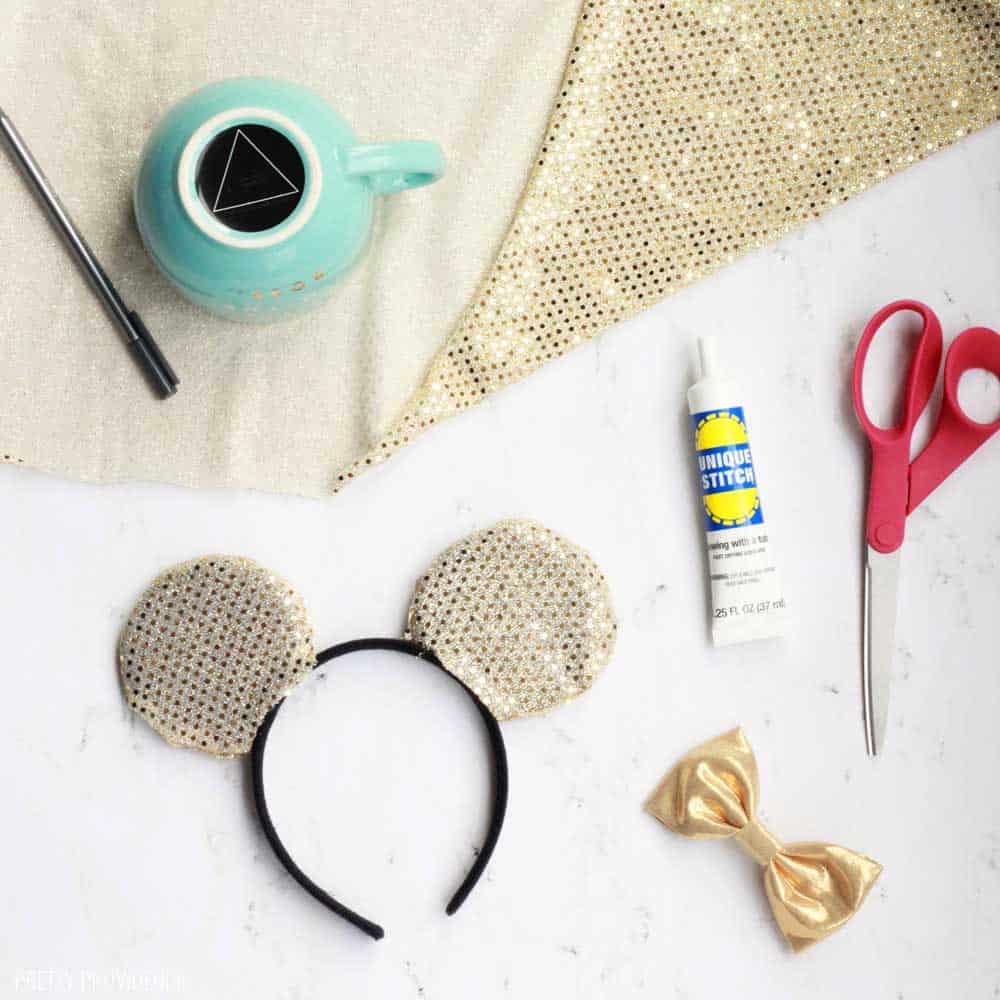 gold fabric, scissors, blue, a gold bow and some minnie mouse ears on a white counter