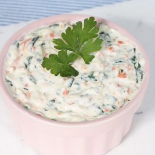 Healthy veggie dip made with yogurt, sautéed vegetables, in a pink bowl and parsley as a garnish.