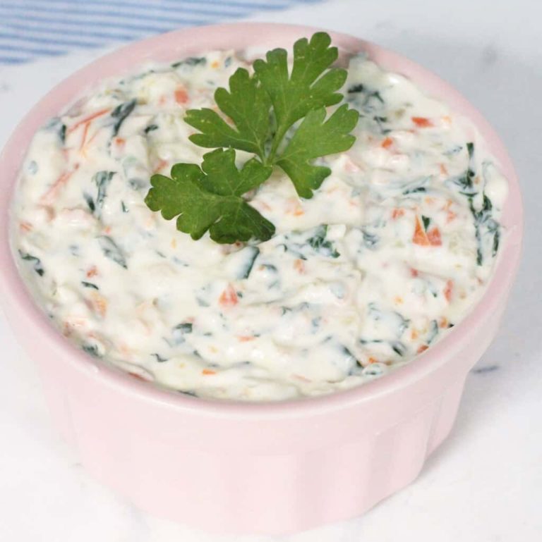 Healthy veggie dip made with yogurt, sautéed vegetables, in a pink bowl and parsley as a garnish.