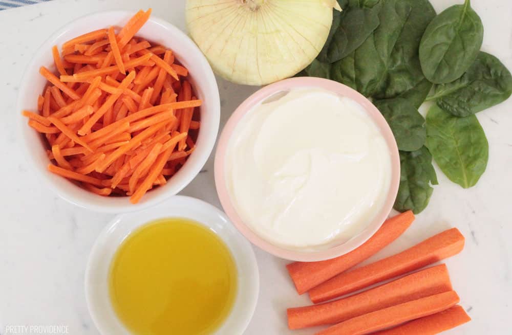 Ingredients for Veggie dip in small bowls, yogurt, olive oil, carrots, onion, spinach.