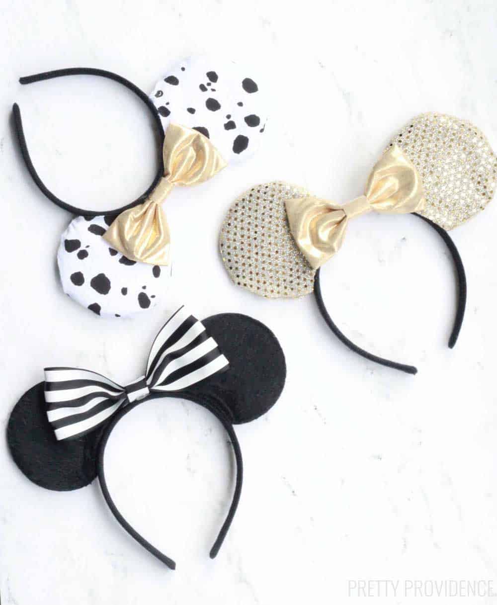 three sets of gold and black minnie mouse ears with different bows on a white counter