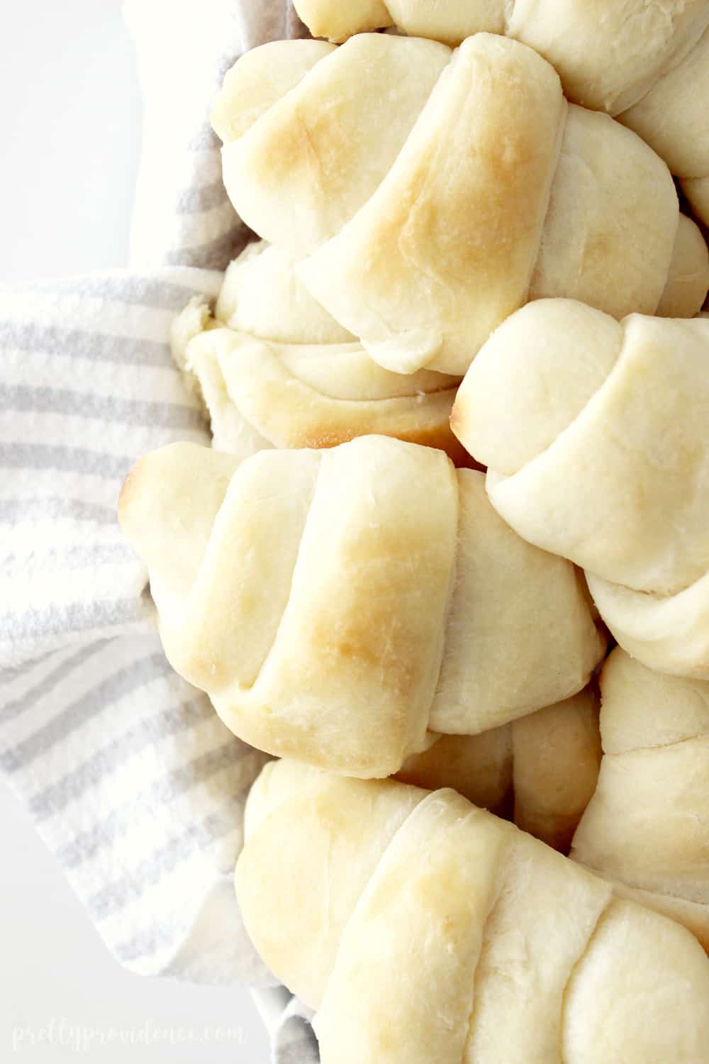 homemade rolls in a basket lined with a grey and white striped tea towel