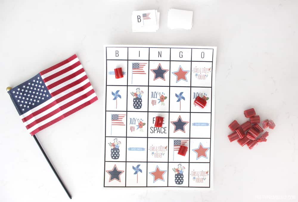 A 4th of July bingo card next to a small flag and a pile of licorice nibs.