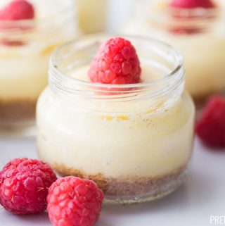 Mini Cheesecakes in jars with raspberries on top.