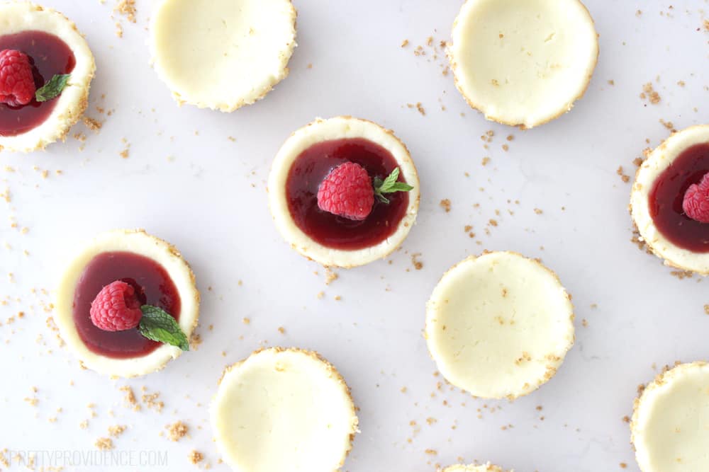 birds eye view of several mini cheesecakes on a white counter with crumbs between them