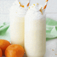 orange julius in a clear glass with whipped cream and orange straws