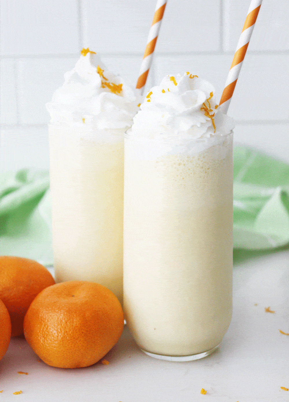 orange julius in a clear glass with whipped cream and orange straws