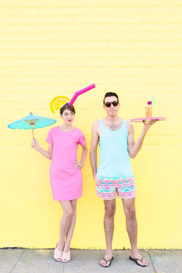a couple dressed up for halloween as tropical drinks against a yellow wall