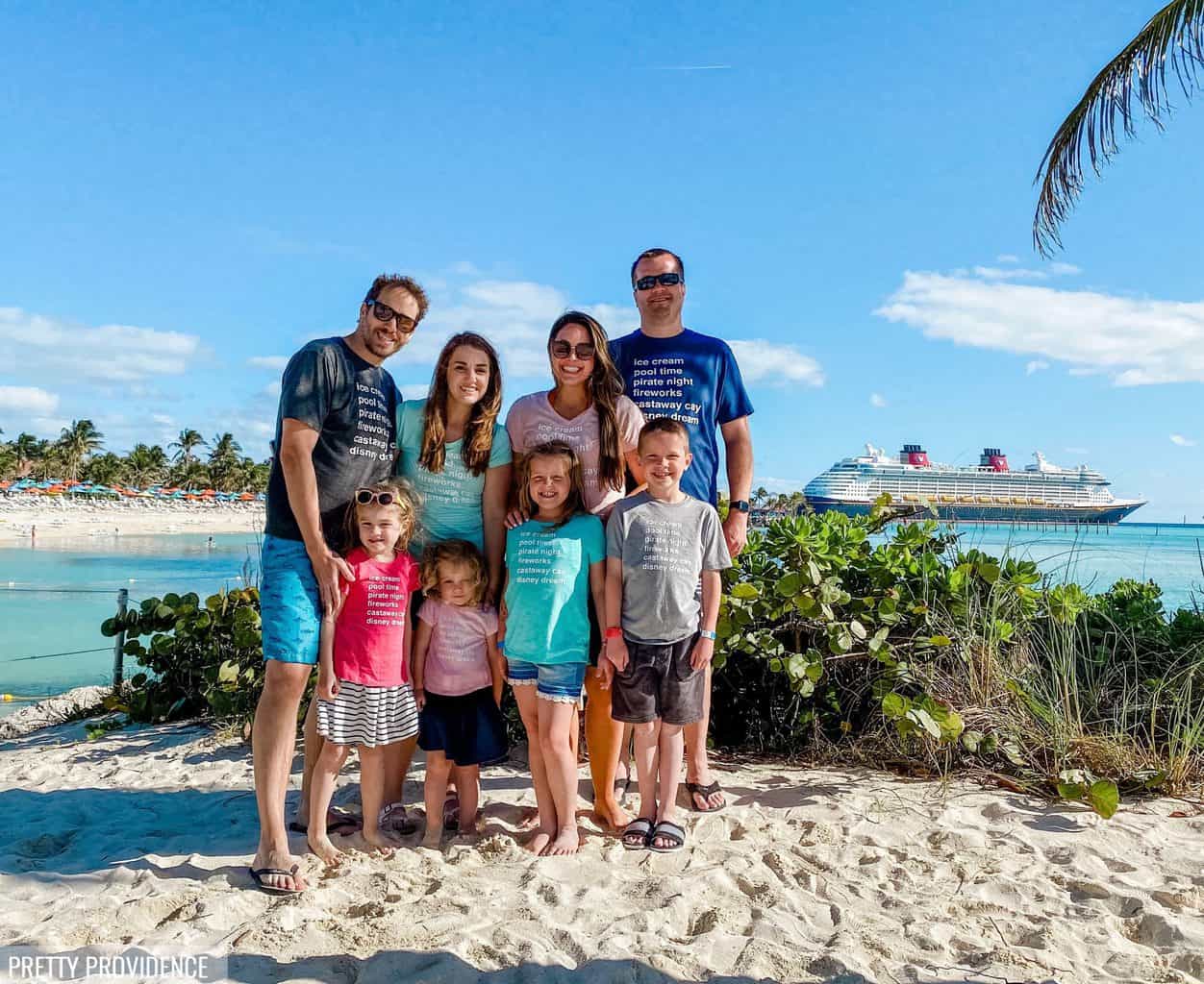 Family wearing matching disney cruise family shirts on Castaway Cay with Disney cruise ship in the background.