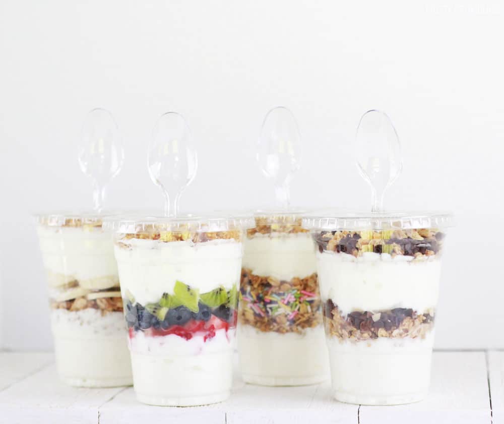 Yogurt parfaits to-go - with spoons sticking out on a white background