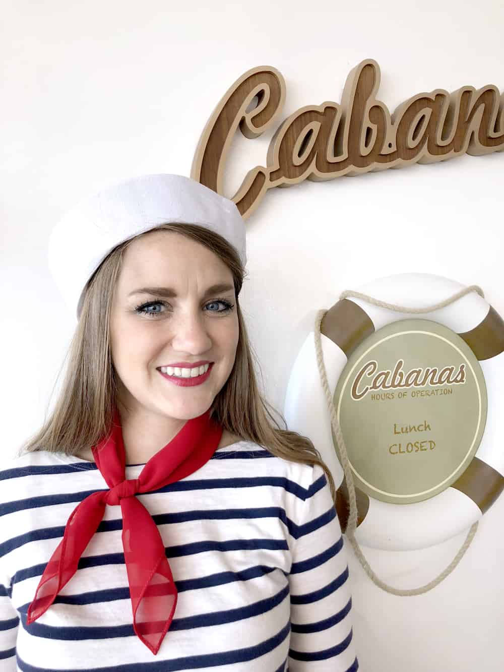 a girl in a sailor costume standing next to a cabanas sign