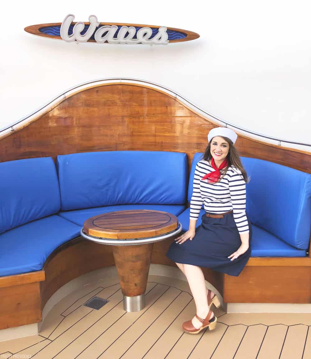 a girl in a sailor costume sitting on a restaurant booth with blue cushions